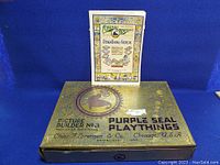 Photo of gold metal play box labeled Purple Seal Playthings with Chas Lorenzen branding, shows vintage condition.