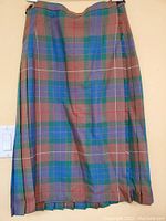 Full view of the brown and green tartan kilt hanging on a hanger