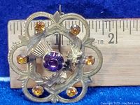 Front view of the Mizpah brooch with amber and amethyst colored stones, ruler included for size reference indicating approximately 25mm width.