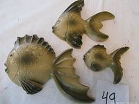 Three blowfish chalkware wall plaques arranged on white cloth showing large, medium, and small sizes, with chip and paint wear visible.