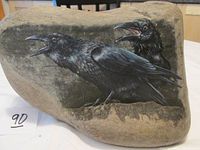 Front view of natural stone with painted image of two ravens perched. Stone and painting details visible.