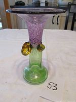 Front view of the vase showing the green base, textured purple upper flute, and two amber-yellow glass knobs.