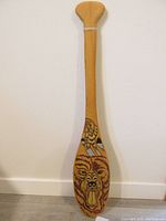 Full view of the paddle showing the wooden surface and hand painted bear head artwork on the blade.