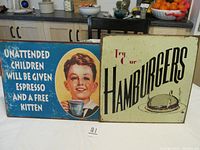 Two metal signs on a kitchen counter showing overall condition and front designs, including text and graphics.