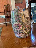 Front view of ceramic garden stool showing detailed floral pattern and gold accents