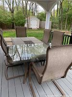 Full view of the rectangular table with removable tile inlays and six matching mesh sling chairs on a wood deck.