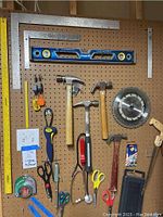 Full overview of pegboard with tools hung including levels, hammers, scissors, saw blade