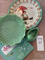 Top view of the ceramic dish with gnome under a mushroom and four jade milk glass plates arranged on top along with two books below.
