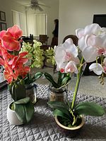 Overview of all four silk orchid arrangements displayed on quilted surface with living room background