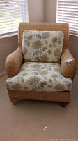 Front view of a Henry Link armchair with woven wicker look frame and floral patterned cushions, showing overall condition and fabric upholstery.