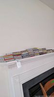 Wide view of a large stack of CDs and cassettes on a white mantel.