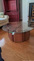 Wide view of round glass coffee table with four round fabric ottomans in a living room setting
