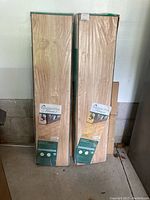 Two packages of Kensington Manor laminate flooring in original wrapping, standing upright against a wall.