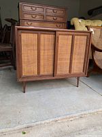 Front view of the media cabinet showing sliding cane doors and tapered legs