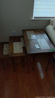 Full set of three wooden nesting tables stacked inside each other showing geometric inlaid designs along the top surfaces.