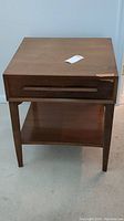 Front view of the nightstand showing single drawer and lower shelf. Some scratches visible on top surface.