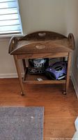 Frontal view of the wooden tea cart showing the removable tray on top with cut-out handles, lower shelf with electronic items not included.
