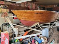 Port side view of wooden hull on white-painted steel trailer with registration number 14K13131 on bow