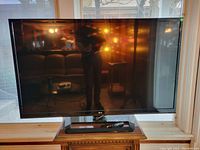 Front view of black 55-inch LG flat-screen TV on stand in room