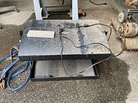 Top view of metal light box with electrical cord and control panel on top, showing dust and wear.