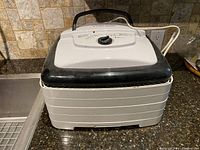 Full view of the Nesco food dehydrator with five stackable trays and a black handle on top.