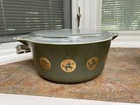 Side angle showing the dark green casserole dish decorated with gold zodiac symbols around exterior.