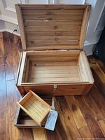 Open wood chest showing interior slats and two smaller wood boxes in front.