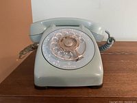Front view of the baby blue rotary phone showing the full rotary dial and handset.