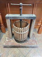 Front view of entire wooden fruit press showing base, frame and screw handle