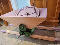 Full view of wooden hopper and gear assembly on painted wooden base.