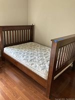 Wide angle view of assembled double wooden bed frame with mattress.