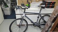 Gray Norco city bike shown against a white cabinet with a flat handlebar, black saddle and visible front and rear 26 inch wheels.