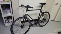Full side view of the black Norco single gear city bike with thin tires and straight handlebars.