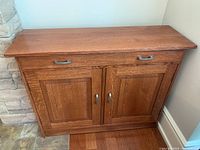 Front view of oak mission style cabinet showing single top drawer with two handles and two paneled doors below