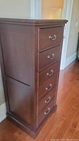 Front-side angle of tall wooden chest showing six drawers with metal bail handles