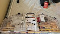 Closed metal mesh carrying case with handle, Sportcraft label on top, glimpses of colored balls and mallets visible through mesh