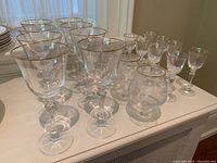 Front view of all stemware including wine glasses, liquor glasses, and brandy snifters shows clear crystal with gold rims.