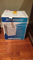 Photo of Simplicity dehumidifier in original box showing brand and product image.