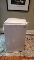 Closed view of white RCA mini bar fridge showing overall condition and brand badge front.