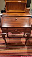 Front view of Stratford drop-front desk showing overall shape, hinged fall-front panel, single drawer and cabriole legs