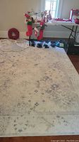 Full view of the cream-colored rug with blue and taupe accents laid on a wood floor with Christmas decorations nearby.