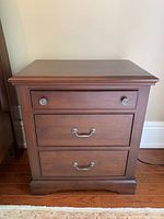 Front view of one side table showing three drawers and hardware