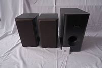 Three Pioneer speakers shown together. Two smaller bookshelf speakers with black fabric grilles and one larger subwoofer speaker with a front port and Pioneer logo.