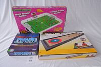 Photo of the three games: Jeopardy board game, World Premier Table Football, Stats 3-in-1 table game with boxes visible on a white background.