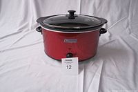 Angled view of red Everstar slow cooker with glass lid and black handles