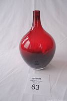 Front view of a red glass vase with a bulbous body and narrow neck on a white background with auction lot number.