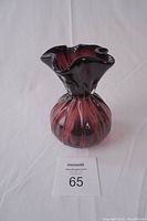 Front angle view of decorative glass vase showing bulbous ribbed design and ruffled top edge.