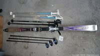 Zone ski with bindings and two sets of ski poles shown on floor