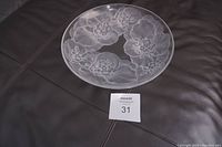 Full overhead view of the large clear glass fruit bowl featuring the etched floral design across its surface, placed on a dark background.