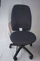Front view of the dark gray high back upholstered office chair showing the seat and backrest with textured olefin fabric.